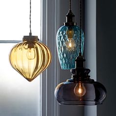 three different colored glass lights hanging from a ceiling