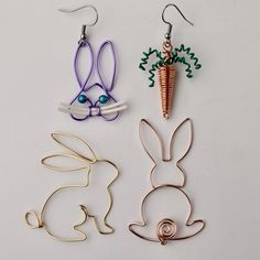 three different colored metal earrings on a white surface, one has a carrot and the other has an earring