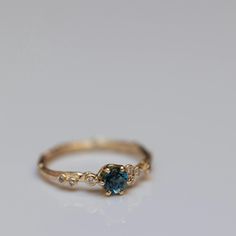 a gold ring with a blue stone and two diamonds on the side, sitting on a white surface