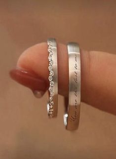 two silver rings with white diamonds on top of each other in the palm of someone's hand