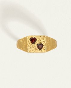 The Venus Signet Ring is a bold statement of love's enduring strength. 
 
Crafted from 18k gold vermeil, its substantial form is softened by twin heart-shaped garnets lovingly set into textured gold. This nostalgic design combines the timeless tradition of Roman signet rings with a modern, romantic twist. 
 
When worn, it becomes a personal talisman, a powerful reminder of love's presence and the cherished commitments we hold dear. Signet Ring Gold, Silversmithing Jewelry, Nostalgic Design, Seal Ring, Roman Goddess, Signet Rings, Goddess Of Love, Diamond Guide, Gold Signet Ring