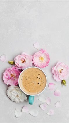 a cup of coffee surrounded by pink flowers