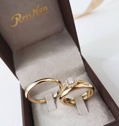 two gold wedding rings sitting in a box