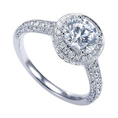 a white gold engagement ring with diamonds on the band and an oval center stone surrounded by round