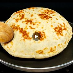 an uncooked pita bread on a pan with a wooden spoon in it