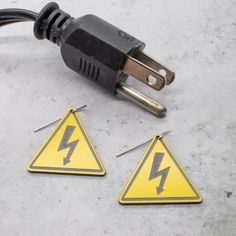 two electrical wires plugged in to a yellow triangle shaped sign with lightning symbols on it