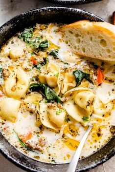 a bowl of pasta soup with bread on the side