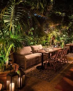 an outdoor dining area is lit up with lights and plants on the table, along with wicker furniture