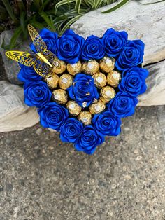 a bouquet of blue roses and chocolates in the shape of a heart with a butterfly on top