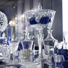 an assortment of blue and white glassware on a table with ornaments in the background