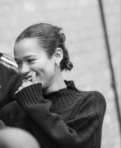 a young woman smiles as she talks on her cell phone while standing next to a man