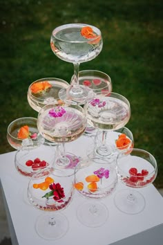 there are many wine glasses with flowers in them on top of a white tablecloth