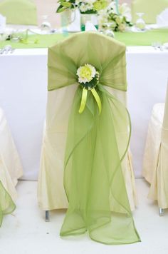 the chair covers are covered with green organes and flower centerpieces at the head table