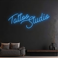 a living room filled with furniture and a neon sign on the wall that says tattoo studio