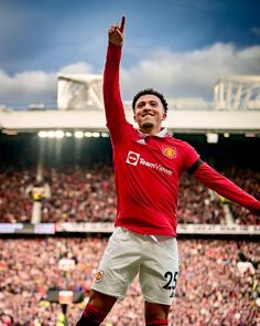 a man in red jersey standing on top of a soccer field with his arms up