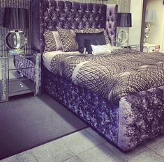 a large bed sitting in a bedroom next to a mirrored dresser and mirror table with two lamps on top of it