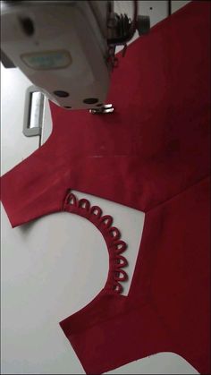 the sewing machine is next to a red dress that has been sewn on it