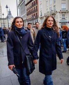 two women walking down the street with their hands in each other's pockets and holding hands