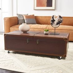 a brown trunk sitting on top of a white rug in front of a tan couch