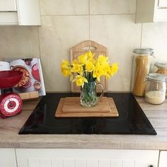 a glass vase with yellow flowers sitting on top of a stove