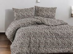 a bed with a leopard print comforter and matching pillow cases on top of it