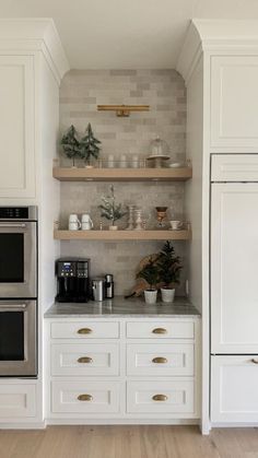 a kitchen with white cabinets and open shelving above the stove, along with two ovens