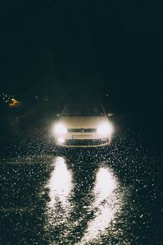 a car driving down the road in the rain at night with its headlights turned on