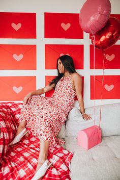 a woman in a red and white dress is sitting on a bed with some balloons