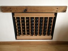 a wooden wine rack filled with lots of bottles on top of a hard wood floor