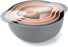 a stack of gray and pink bowls with spoons in them on a white background