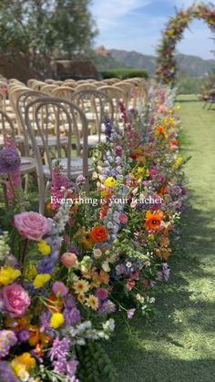 rows of chairs lined up with flowers in the foreground and an arch to the right