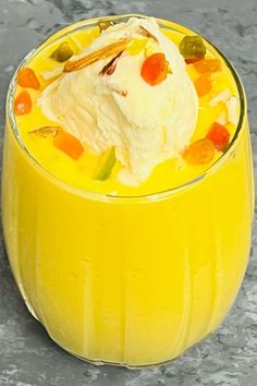 a yellow glass filled with fruit and ice cream on top of a gray countertop