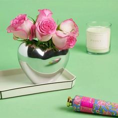 there is a vase with pink roses in it and a pen on the table next to it