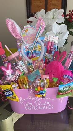 a pink basket filled with lots of candy and candies on top of a table