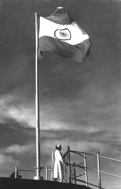 a man standing on top of a boat next to a flag