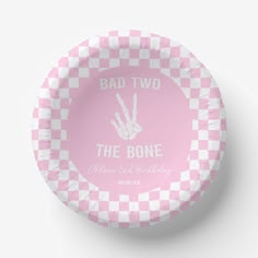 a pink and white checkered paper plate with the words bad two, the bone on it