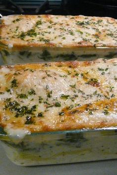 two rectangular casserole dishes with cheese and herbs on top, sitting on the stove