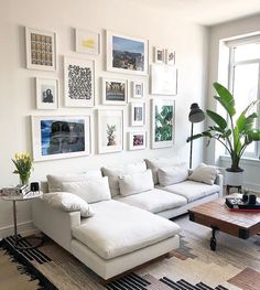 a living room filled with white furniture and pictures on the wall above it's coffee table