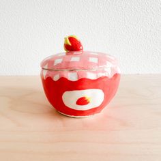 a red and white bowl sitting on top of a wooden table