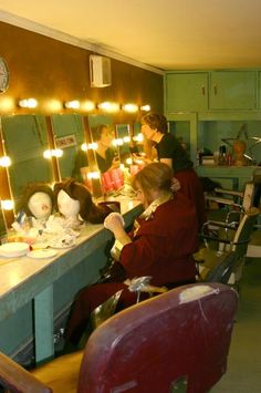 a woman sitting in front of a mirror while getting her hair done at a salon