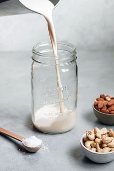 a spoon pouring almonds into a glass jar