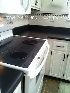 a stove top oven sitting inside of a kitchen next to white cabinets and counter tops