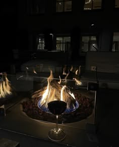 a glass of wine sitting in front of a fire pit with flames coming out of it