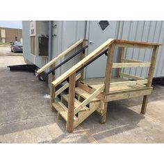 two wooden steps sitting next to each other in front of a metal container and building