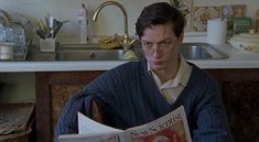 a man reading a newspaper in the kitchen