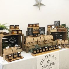 there are many different items on display at the market table, including jams and candles