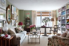 a living room filled with furniture and lots of books on the shelves in front of a window