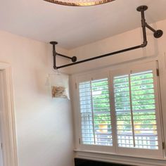 a lamp hanging from the ceiling over a fireplace in a room with white walls and windows