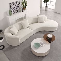 a large white couch sitting on top of a gray floor next to a coffee table