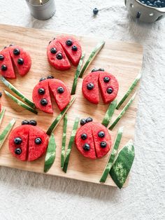 watermelon and blueberries are arranged in the shape of ladybugs on a cutting board